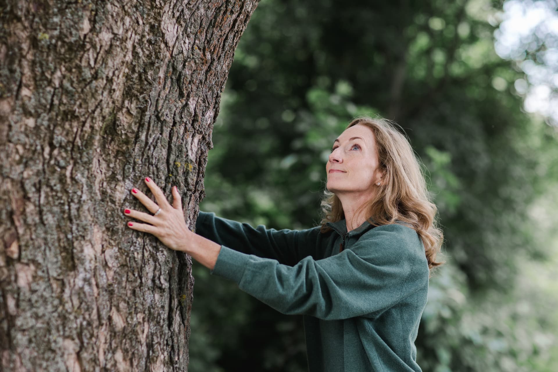 Pia with her hands on a tree trunk in the forest